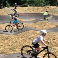 Kinder fahren mit Rädern über die Bikepark-Landschaft. 