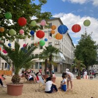 Die Passanten sonnen sich auf Liegestühlen am Stadtstrand mitten in Augsburg.