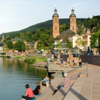 Im Abendrot sonnen sich Leute auf den warmen Steinen der Uferzone. 