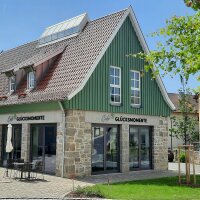 Die sanierte steinerne Fassade im Erdgeschoss mit der grünen Holzverkleidung im Obergeschoss lockt ins Café. 