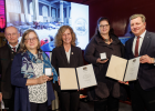 Verkehrsminister Christian Bernreiter überreicht Urkunden und Medaillen an drei Frauen. Daneben steht der Laudator.