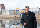 Verkehrsminister Christian Bernreiter steht am Ufer des Main-Donau-Kanals. Im Hintergrund Hafengebäude.