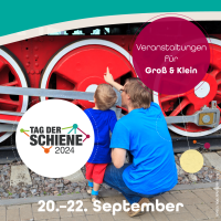 Vater und Sohn schauen sich eine Lokomotive am Tag der Schiene an.