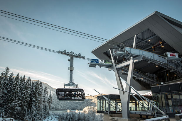 Seilbahn-Zugspitze-Bayerische-Zugspitzbahn-Bergbahn
Gondel fährt von einer Bergstation ab durch eine verschneite Berglandschaft